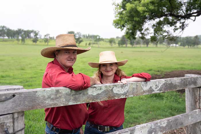 A photo of Kylie and Phil George leaning on a fence