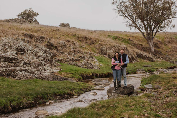 Woman and man holding baby standing next to creek.