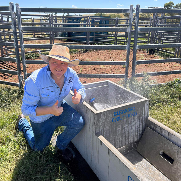 Man kneeling next to concrete water trough.