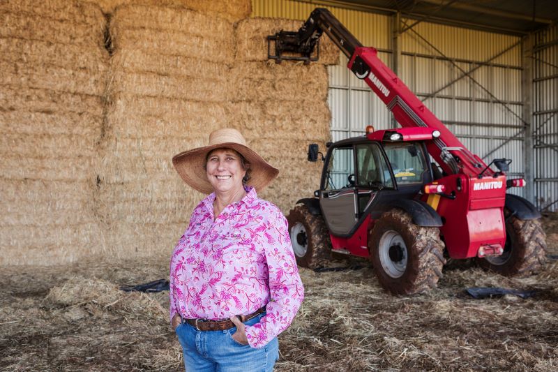 Woman standing in front of haybales and machinery